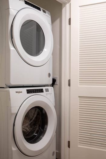 Two white Whirlpool washing machines stacked on top of each other.